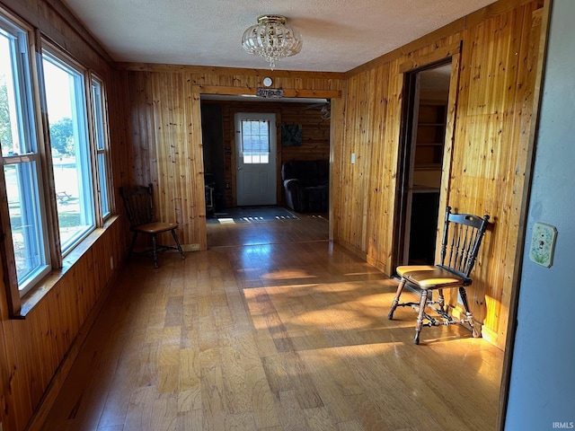 hall featuring wood-type flooring, a textured ceiling, and wood walls