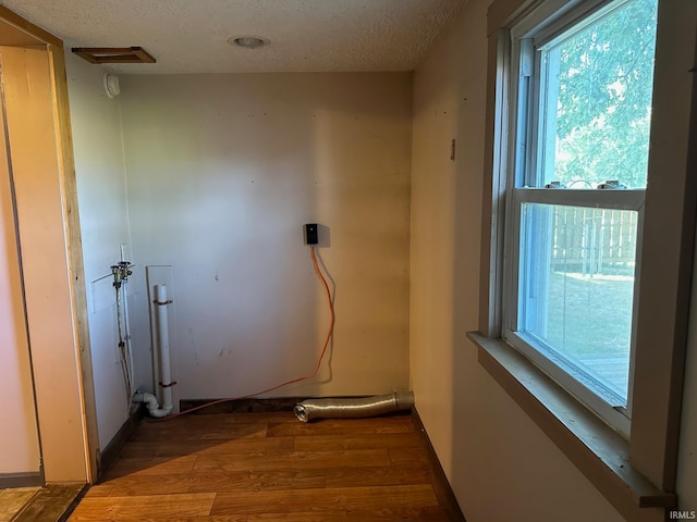 laundry area featuring wood-type flooring and a textured ceiling