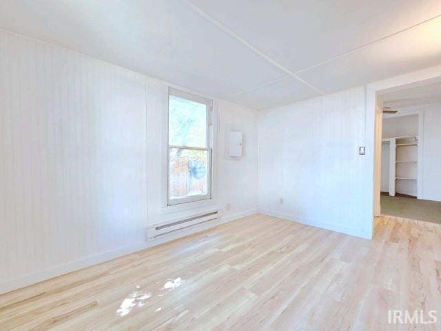 unfurnished room featuring a baseboard radiator and light wood-type flooring