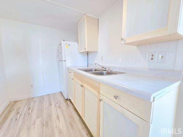 kitchen with light hardwood / wood-style flooring, sink, and white fridge