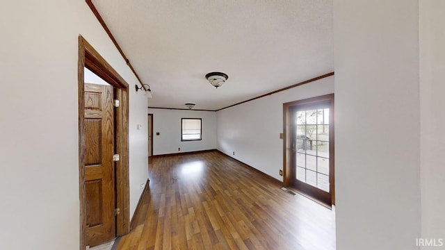 unfurnished room with a textured ceiling, wood-type flooring, and ornamental molding