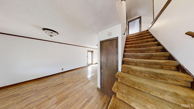 stairs featuring wood-type flooring and a textured ceiling