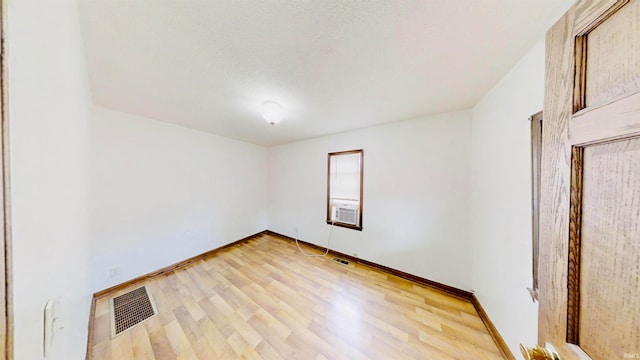 unfurnished room with cooling unit and light hardwood / wood-style floors