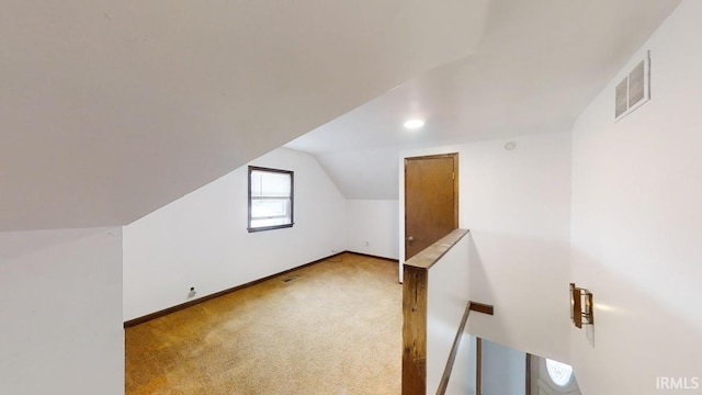 bonus room with lofted ceiling and light colored carpet