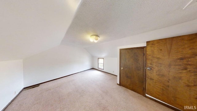 bonus room with a textured ceiling, lofted ceiling, and carpet