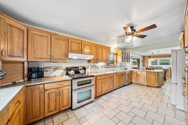 kitchen featuring ceiling fan, sink, kitchen peninsula, backsplash, and appliances with stainless steel finishes