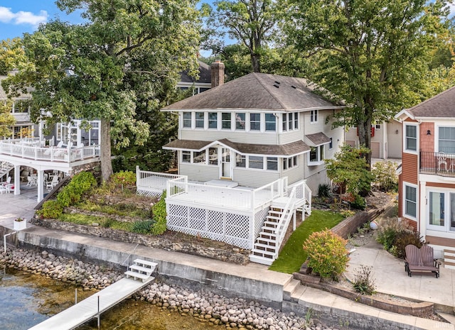 back of property with a deck with water view and a patio area