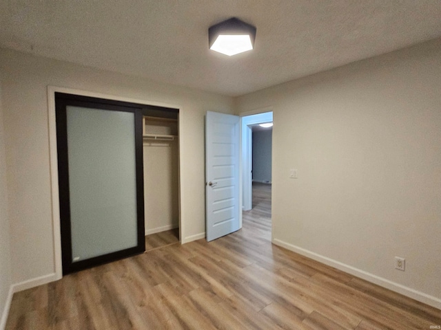 unfurnished bedroom featuring a textured ceiling, a closet, and hardwood / wood-style floors