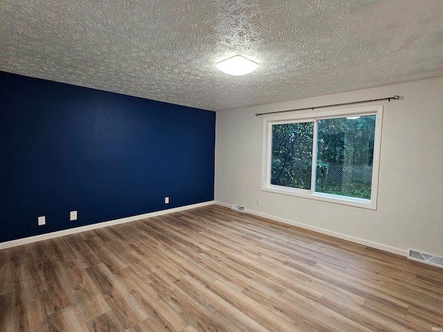 empty room featuring light wood-type flooring and a textured ceiling