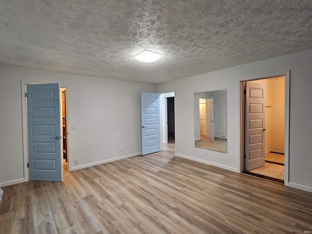 spare room with a textured ceiling and light hardwood / wood-style flooring