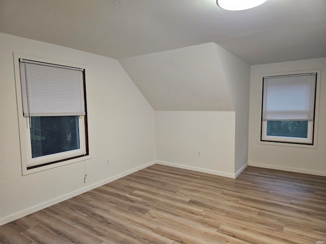 additional living space with light wood-type flooring and lofted ceiling