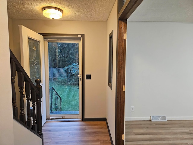 doorway featuring wood-type flooring and a textured ceiling