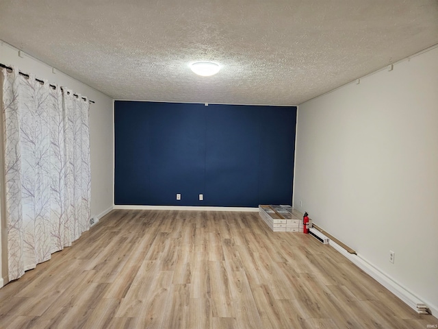 empty room with light wood-type flooring and a textured ceiling