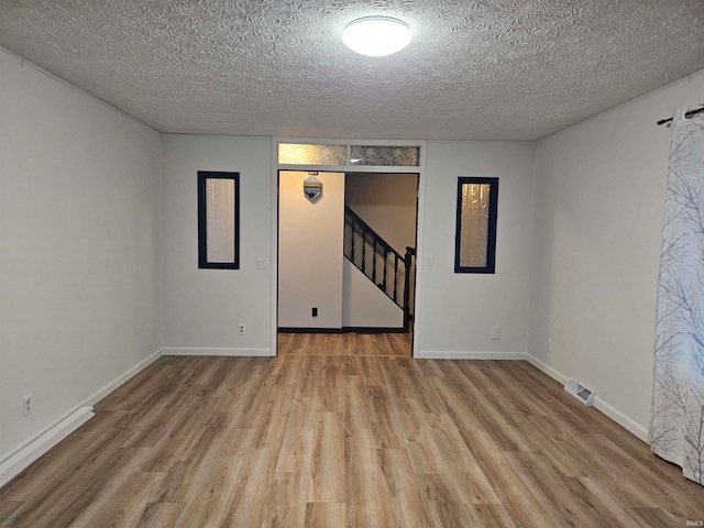 interior space featuring light wood-type flooring and a textured ceiling