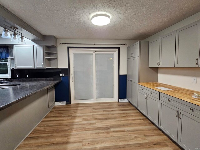 kitchen featuring a textured ceiling, light hardwood / wood-style flooring, and butcher block counters