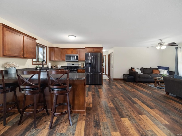 kitchen featuring dark hardwood / wood-style floors, sink, a kitchen bar, stainless steel appliances, and ceiling fan