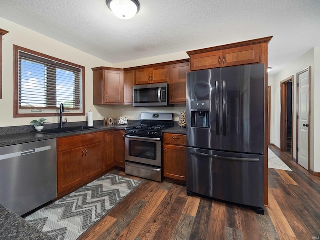 kitchen featuring a textured ceiling, appliances with stainless steel finishes, dark hardwood / wood-style floors, and sink