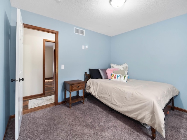 bedroom featuring a textured ceiling and dark carpet