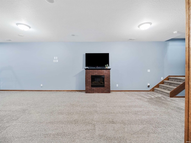 unfurnished living room featuring a textured ceiling, carpet flooring, and a brick fireplace