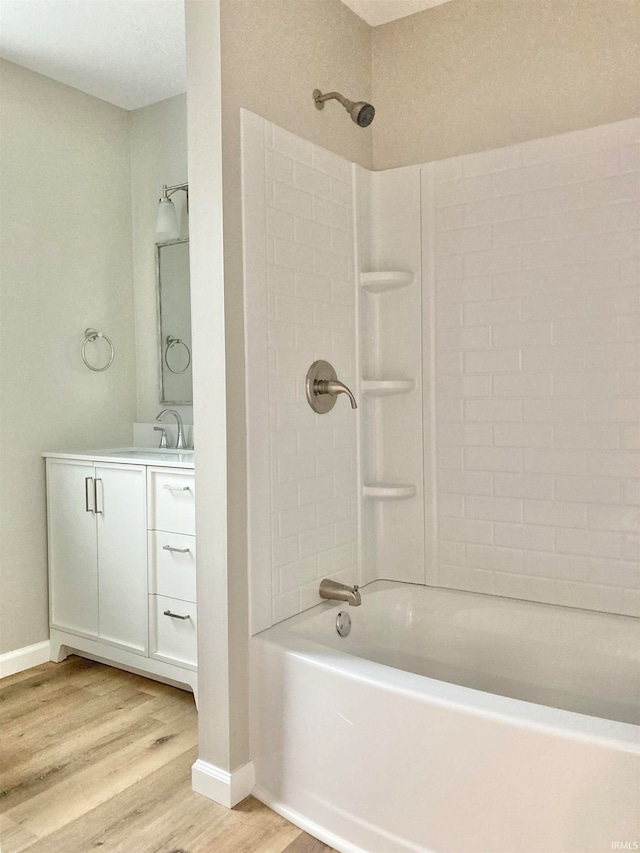 bathroom with hardwood / wood-style floors, tiled shower / bath, and vanity