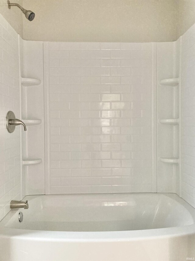 bathroom featuring a textured ceiling and tiled shower / bath combo