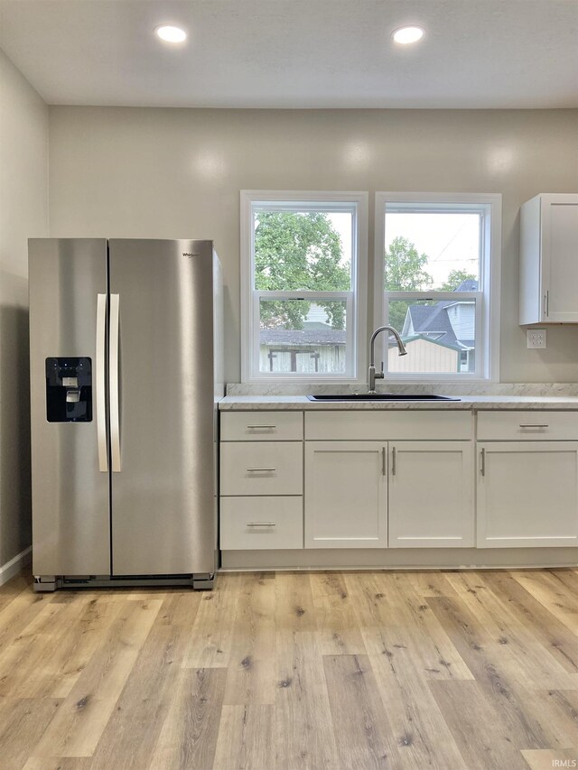 kitchen with stainless steel fridge, light hardwood / wood-style floors, sink, and white cabinets