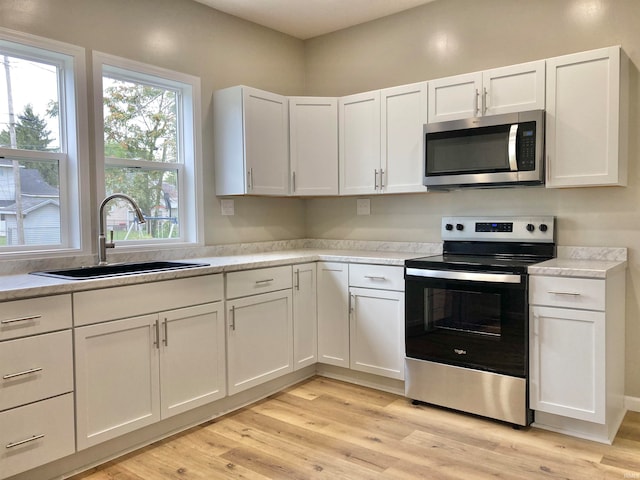 kitchen with white cabinetry, sink, light hardwood / wood-style flooring, and stainless steel appliances