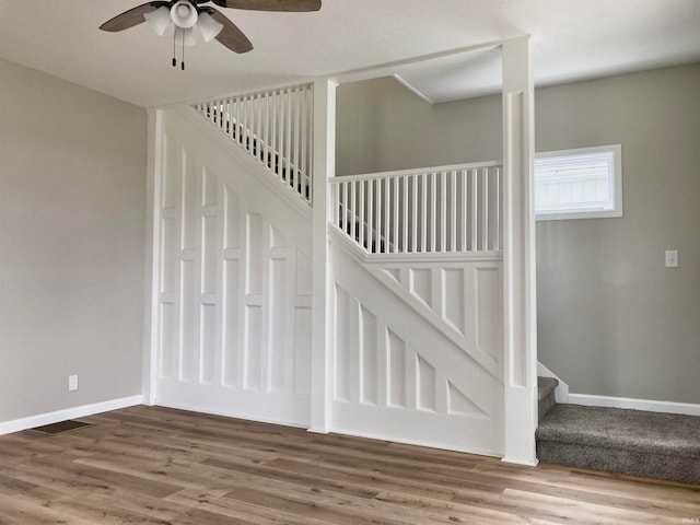 stairway with ceiling fan and hardwood / wood-style flooring