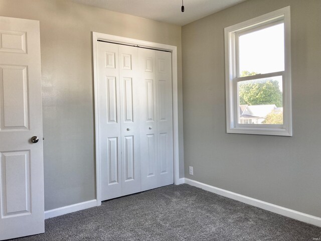 unfurnished bedroom featuring dark colored carpet and a closet