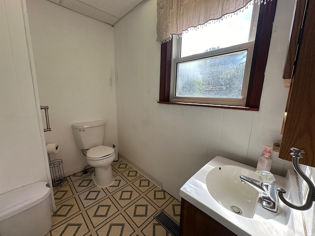 bathroom featuring a paneled ceiling, vanity, toilet, and tile patterned floors