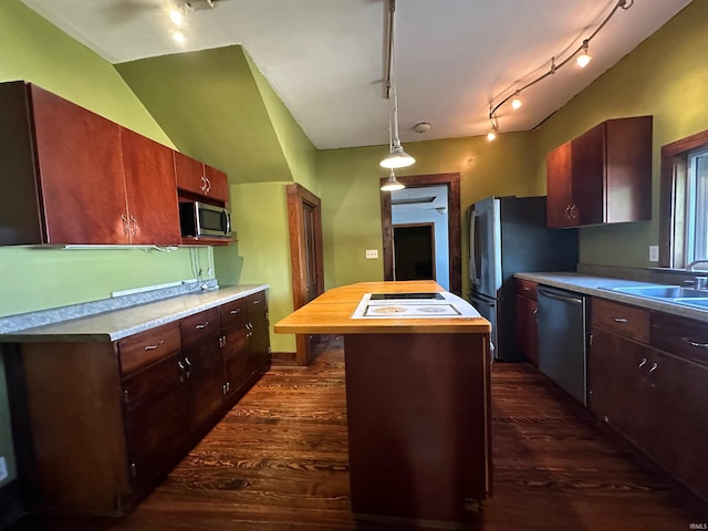 kitchen featuring lofted ceiling, a kitchen island, track lighting, appliances with stainless steel finishes, and dark hardwood / wood-style floors