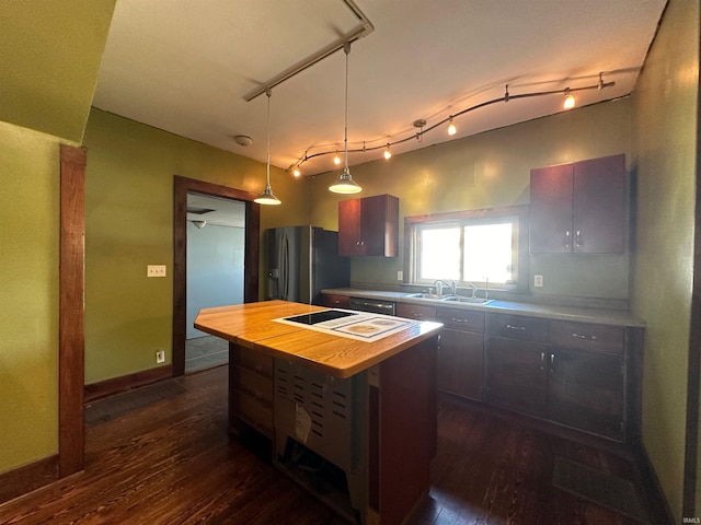 kitchen featuring decorative light fixtures, dark wood-type flooring, stainless steel appliances, a center island, and wood counters