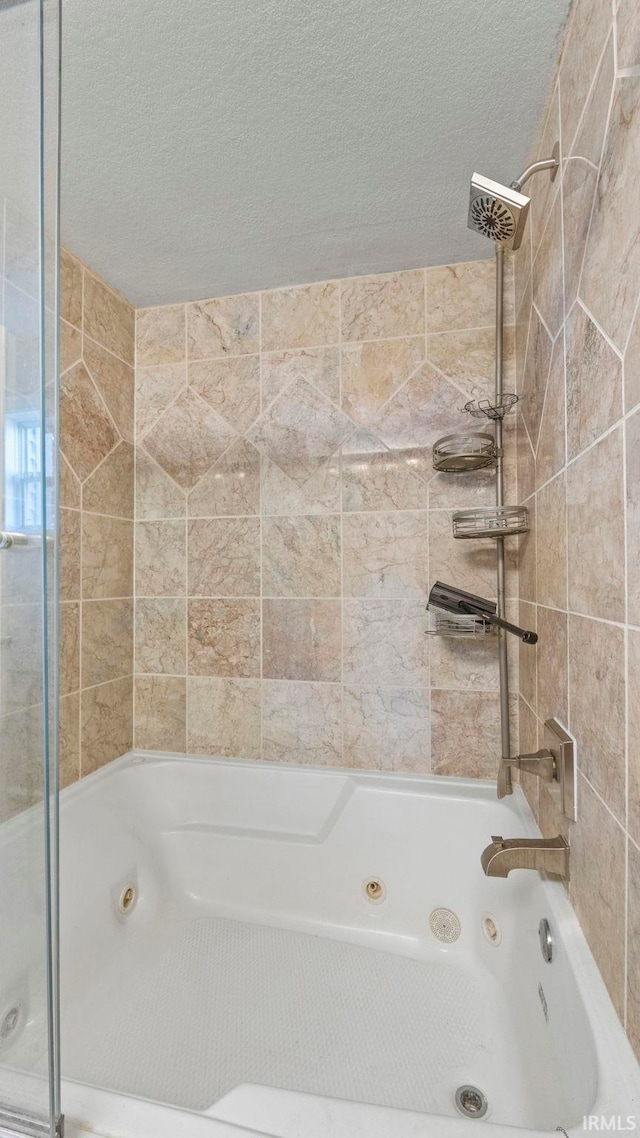 bathroom with a textured ceiling and tiled shower / bath combo