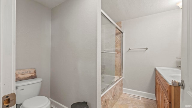 full bathroom with a textured ceiling, bath / shower combo with glass door, vanity, and toilet