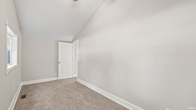 spare room featuring carpet and lofted ceiling