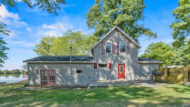 view of front facade with a water view, a patio area, french doors, and a front yard