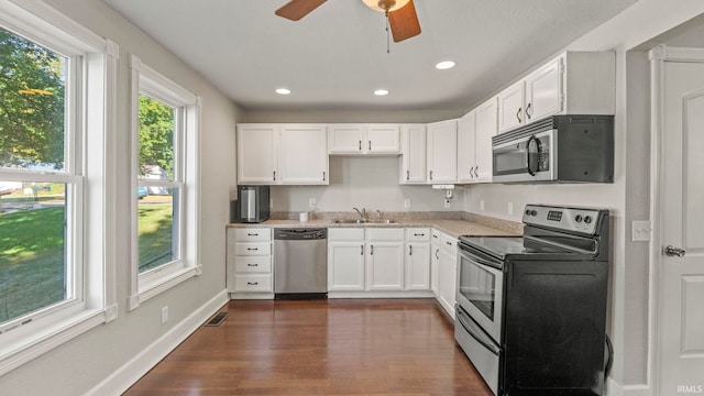 kitchen featuring appliances with stainless steel finishes, dark wood-type flooring, white cabinets, ceiling fan, and sink