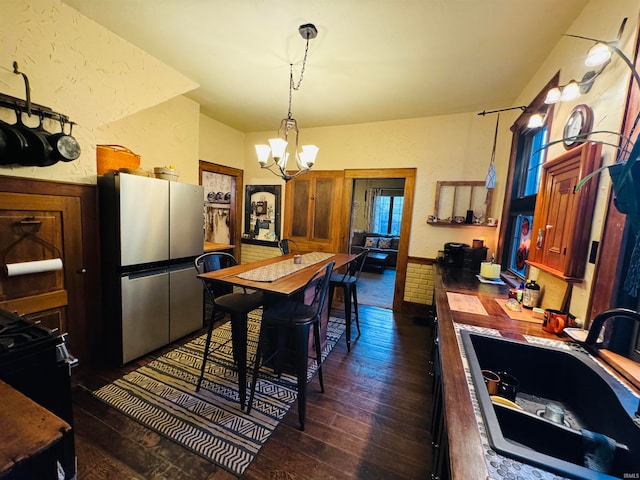 dining space with an inviting chandelier, dark wood-type flooring, and sink