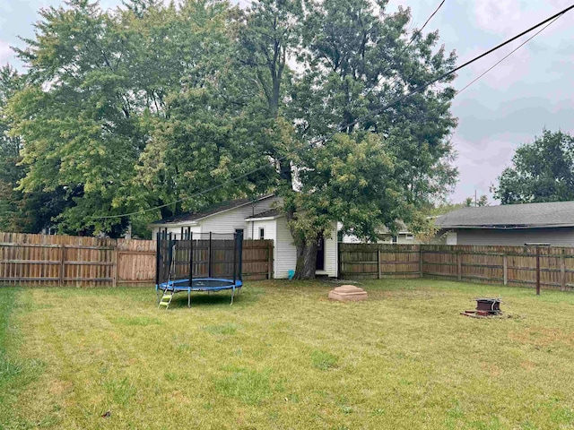 view of yard featuring a trampoline and an outdoor fire pit