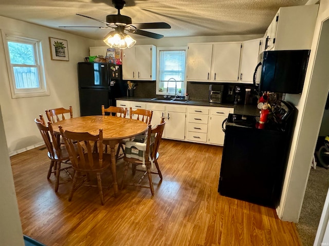 kitchen featuring ceiling fan, black fridge, sink, and white cabinets