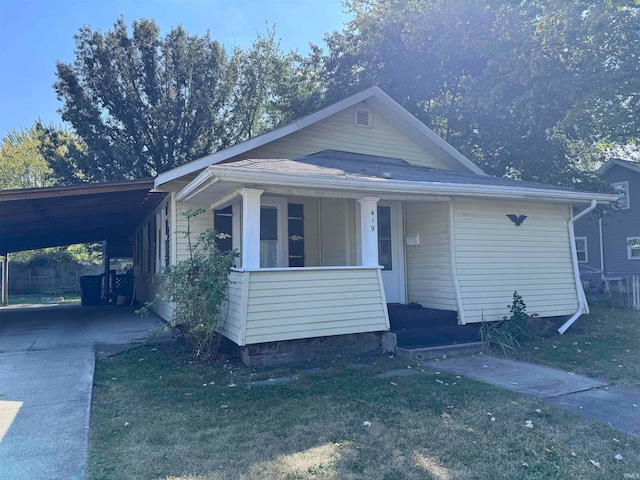 view of front of property featuring a front lawn, a carport, and covered porch