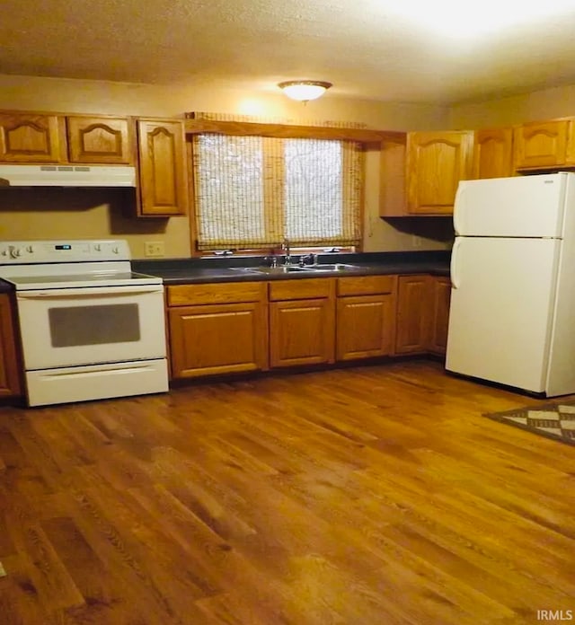 kitchen featuring white appliances, a textured ceiling, sink, and dark hardwood / wood-style flooring