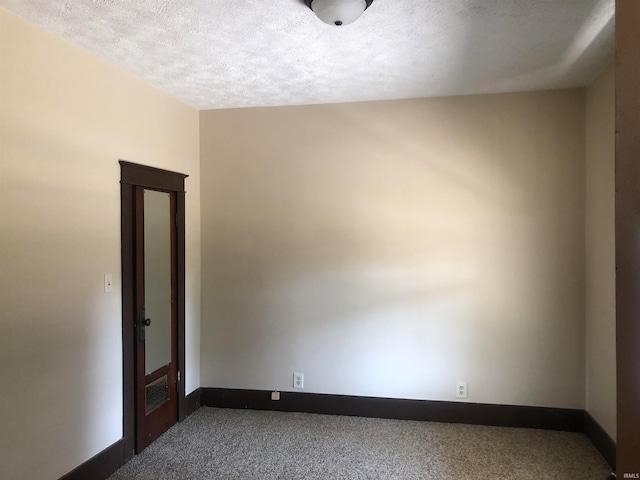 carpeted empty room featuring a textured ceiling