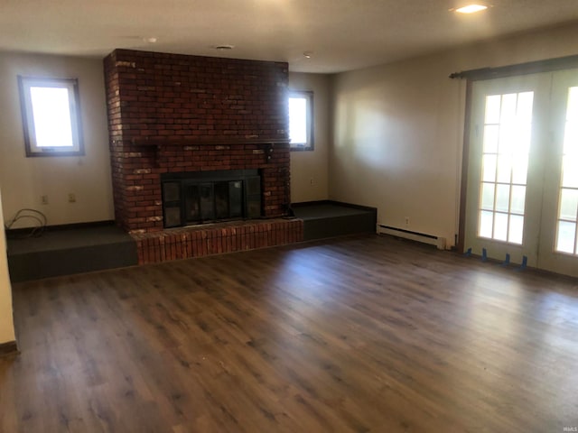 unfurnished living room with a brick fireplace, a baseboard radiator, and dark wood-type flooring