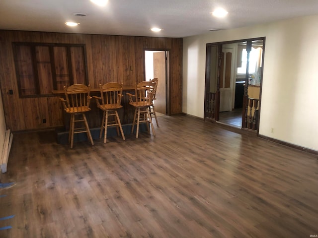 dining area featuring wooden walls, indoor bar, and dark hardwood / wood-style floors