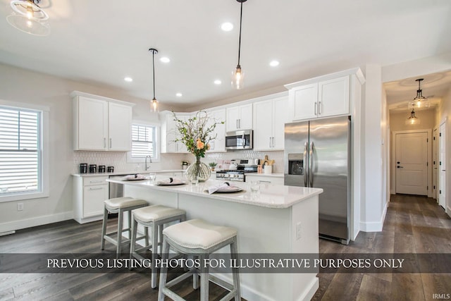 kitchen featuring white cabinets, a center island, stainless steel appliances, and decorative light fixtures