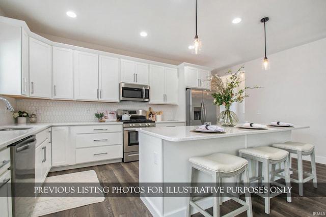 kitchen featuring decorative light fixtures, appliances with stainless steel finishes, white cabinets, and dark hardwood / wood-style flooring