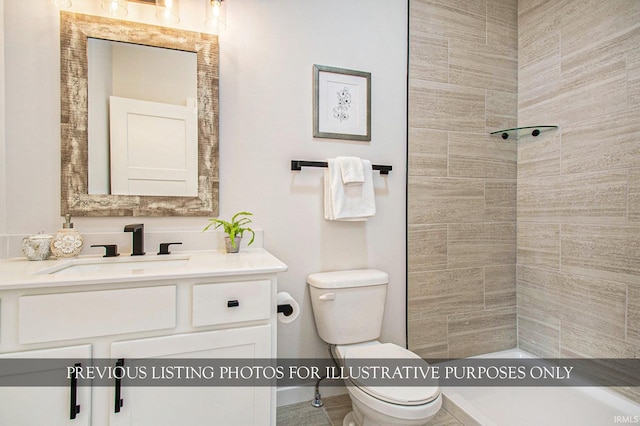 bathroom featuring a tile shower, vanity, and toilet