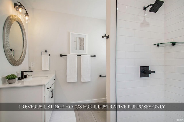 bathroom with a tile shower and vanity