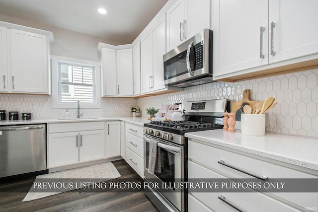 kitchen featuring white cabinets, backsplash, stainless steel appliances, hardwood / wood-style flooring, and sink